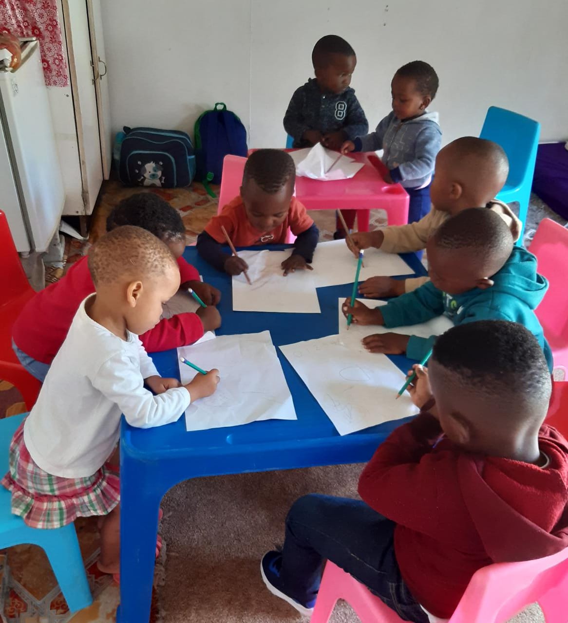 Children drawing together at classroom tables