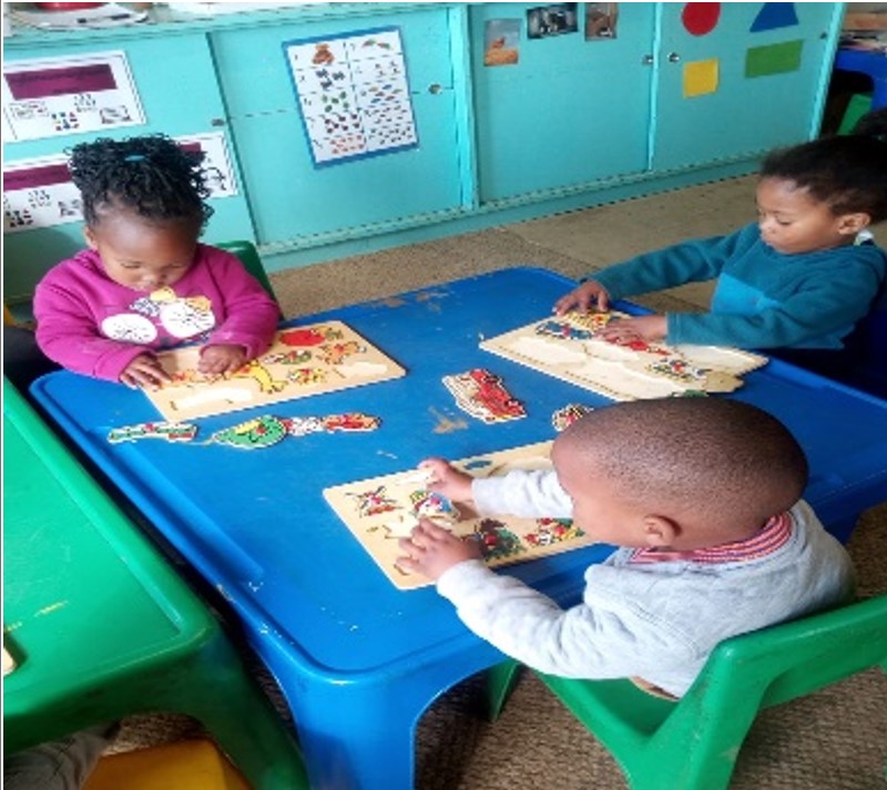 Children working on puzzles around a classroom table