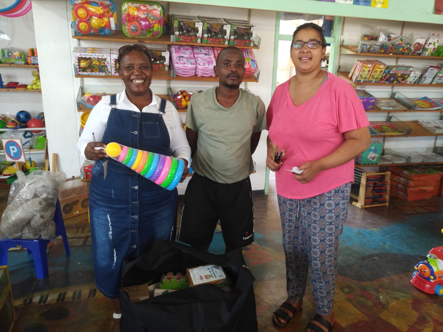 Three adults with educational toys and classroom supplies in a shop
